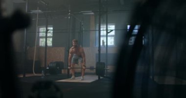 Geniş açıda, beyaz tenli aşırı halterci bir sporcunun, ağır halterlerle spor salonundaki büyük spor salonunda çalışması..