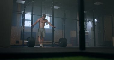 Çıplak gövdeli sakallı genç adam spor salonundaki yoğun egzersizden sonra derin bir nefes alıyor. Genç, sakallı, yorgun erkek için ağır stres eğitimi kavramı. Spor salonunda sıkı çalıştıktan sonra dinleniyor.