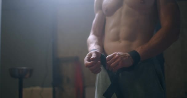 Jeune homme athlétique caucasien changer, mettre des sangles de levage de poids dans le vestiaire de la salle de gym avant l'entraînement au ralenti. attaches bras à haltère avec sangles de fitness. — Video
