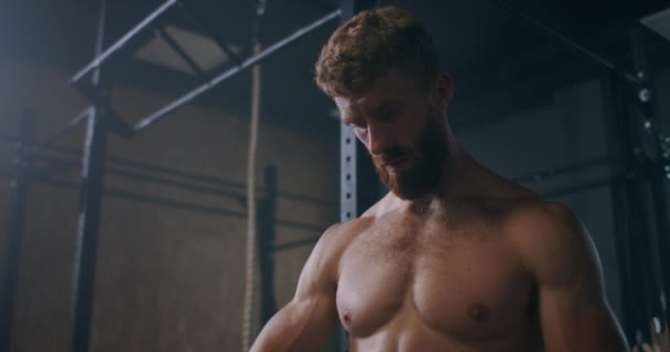 Jeune homme athlétique caucasien changer, mettre des sangles de levage de poids dans le vestiaire de la salle de gym avant l'entraînement au ralenti. attaches bras à haltère avec sangles de fitness. — Video