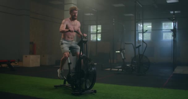 Ung man som använder motionscykel på gymmet. Fitness Man använder air bike för konditionsträning på gym. Utrustning, ansträngning. — Stockvideo