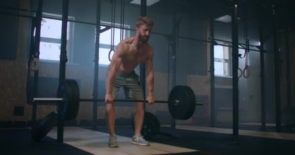 Wide shot of young Caucasian extreme weightlifting athlete man working out with heavy barbell in large hardcore gym hall. — Stock Video