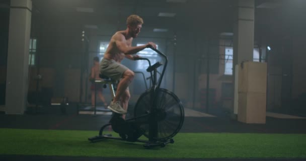 Fitness man op de fiets doet spinning in de sportschool. Fit jonge man uit te werken op sportschool fiets. Mannelijke training op de fiets in een fitnessclub — Stockvideo