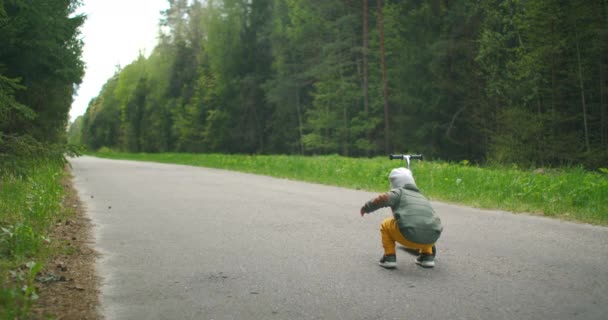 Boy apprend à conduire un scooter dans un parc de la ville. Enfant garçon équitation scooter. — Video