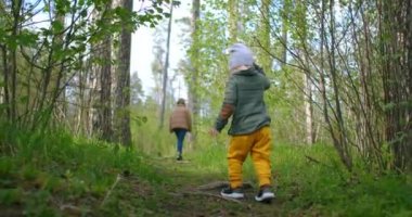 Oğlan güneşli yaz gününde annesini orman yolunda takip ediyor.