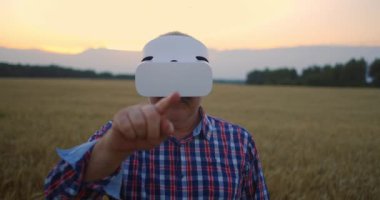 Tahıl tarlasında sanal gerçeklik kaskı takmış kıdemli çiftçi. Gün batımında, traktör sürücüsü olan yaşlı bir adam sanal gerçeklik gözlüğü kullanıyor. VR teknolojileri ve modern tarım sektörü