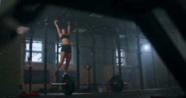 Jimnastik salonunda ayaklarını bara kaldırma çekici kadın egzersizi ve spor salonunda antrenman yapma. Yatay bir çubukta duran bayan sporcu karın kaslarını çalıştırmak için bacaklarını kaldırır.