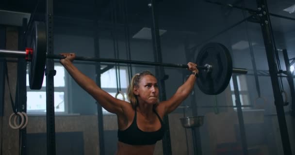 Slow motion: Träningsknappar med skivstång över huvudet. Muskulösa kvinnliga lyft skivstång över huvud träning axlar på gym. självsäker fitness kvinna tränar kraft träning med tung utrustning. — Stockvideo
