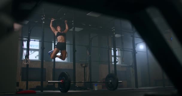 Seorang wanita atletik yang kuat melakukan pull-UPS di sebuah bar horisontal di gym. latihan. — Stok Video