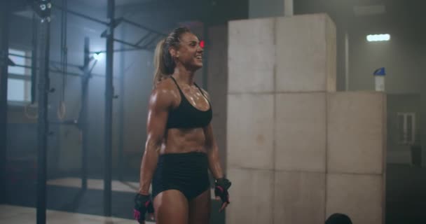 Una mujer cansada y feliz en el gimnasio, su cuerpo radiante de sudor, se ríe y sonríe después de un duro entrenamiento. el placer de los deportes — Vídeos de Stock