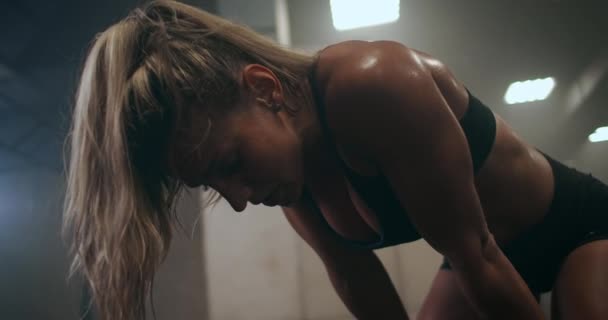 Mujer cansada y agotada después de un duro entrenamiento en el gimnasio está sentada en el suelo y respirando duro. Atleta profesional se está preparando para las competiciones. El trabajo duro y la superación de sí mismo, y el dolor . — Vídeo de stock