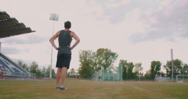 Yorgun bir cirit atıcısı stadyumdaki bir adam mızrak topluyor. Her şey için hazırlanıyorum. Stadyumun arka planında antrenmandan sonra yürümek ve fırlatmak için mızrak taşımak..
