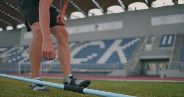 Close-up: Hand een mannelijke atleet in het stadion neemt een speer voor het gooien en bereidt zich voor op een worp te maken. Goes neemt de speer. Training van een speerwerper — Stockvideo