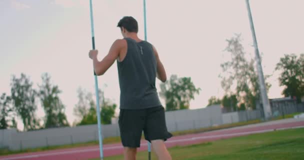 Un lanciatore di giavellotti stanco allo stadio durante l'allenamento infila una lancia nel terreno — Video Stock