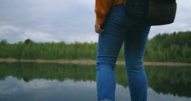 Arka plan: Sırt çantalı bir kadın gezgin, ahşap bir iskelede duran bir dağ ormanı gölünün güzelliğinin tadını çıkarıyor. Yalnız kadın yolculuğunun yavaş çekim konsepti. Karantina ve seyahat