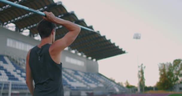 Zpomalený pohyb: mužský atlet na stadionu se soustředí a hodí oštěpem. Příprava na olympijské hry všude kolem — Stock video