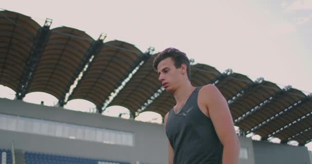 Vermoeide speerwerper... een man in het stadion verzamelt speren. Ik bereid me voor op alles. Wandelen door het stadion na training op de achtergrond van de tribune en het dragen van speren voor het werpen. — Stockvideo