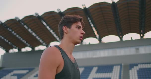 Oszczep Thrower spaceruje po stadionie z włóczniami i je zbiera. Idź z włócznią w ręku na tle stadionu stoi. Szkolenie mistrza olimpijskiego. — Wideo stockowe