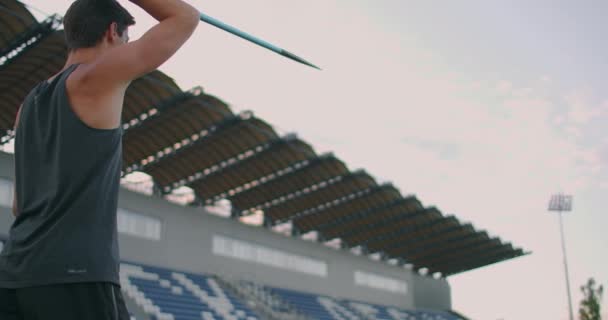 Sportivul care face javelină aruncă pe teren atletic. Un atlet de sex masculin aruncă javelina pe stadionul olimpic. Sportiv îmbrăcat în haine sportive pe pista sportivă din stadionul profesionist — Videoclip de stoc