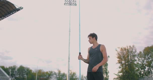 Speerwerpen atleet werper terug in track and field event. Ongedefinieerde atleet speerwerpen tijdens de kampioenschappen atletiek. Sportman oefent speerwerpen tegen blauwe lucht met wolken — Stockvideo