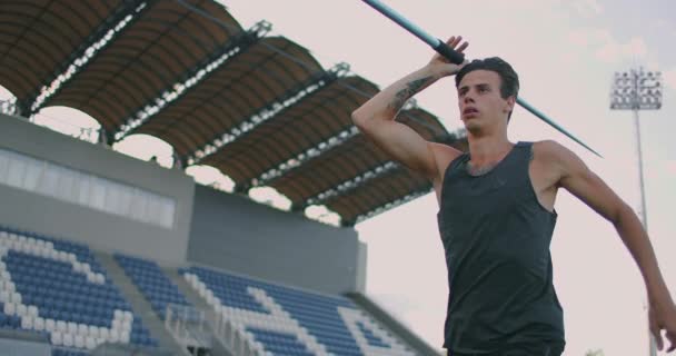 Carrera y lanzamiento de jabalina en el estadio. Slo-Mo Shot of Young Man Throwing Javelin. Un hombre caucásico lanza jabalina en el estadio — Vídeos de Stock