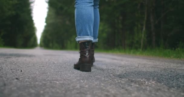 De cámara lenta convertir primer plano, que los zapatos de viajero están caminando por la carretera en jeans. Los zapatos van por un sendero forestal en el asfalto — Vídeos de Stock