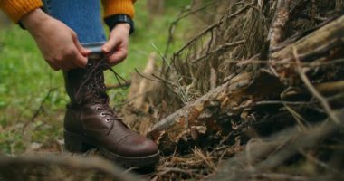 Ormandaki gezginlerin ayakkabılarına ayakkabı bağlayan ellerin yakın çekimi. Orman gezisi