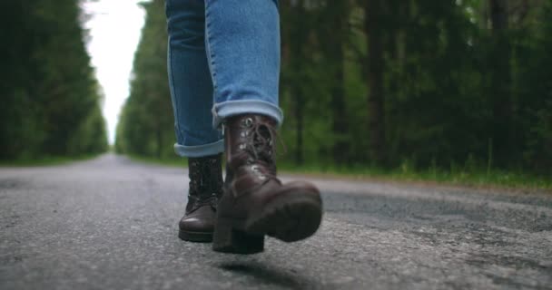 De cámara lenta convertir primer plano, que los zapatos de viajero están caminando por la carretera en jeans. Los zapatos van por un sendero forestal en el asfalto — Vídeos de Stock