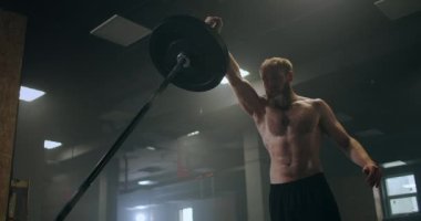 Tek Kollu Mayın Basına Çömelme egzersizi yapan adam. Spor salonunda halter egzersizi yapan bir adam. Güçlü adam mayın egzersizi yapıyor, halterle egzersiz yapıyor..