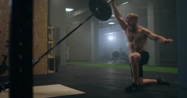 Erkek bir sporcu bir eli ağır çekimde ağırlık kaldırır. Bir boksör için dayanıklılık eğitimi. Adam spor salonunda çalışırken terliyor. Yumruk darbesini elleriyle uyguluyor.