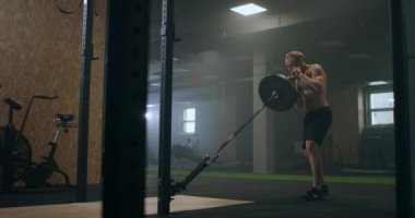 Tek Kollu Mayın Basına Çömelme egzersizi yapan adam. Spor salonunda halter egzersizi yapan bir adam. Güçlü adam mayın egzersizi yapıyor, halterle egzersiz yapıyor..