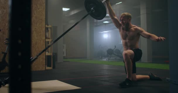 En manlig idrottare lyfter en hantelstång med ena handen i slow motion. Styrketräning för boxare. Han svettas i gymmet och övar på kraften av slaget med handen. — Stockvideo