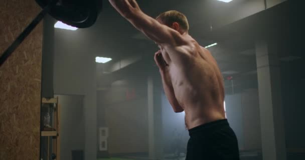 En manlig idrottare lyfter en hantelstång med ena handen i slow motion. Styrketräning för boxare. Han svettas i gymmet och övar på kraften av slaget med handen. — Stockvideo