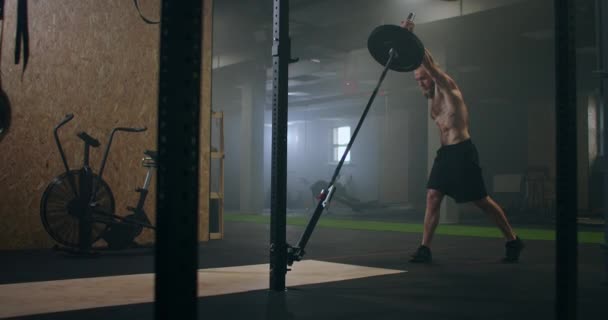 Un combattente di sesso maschile che si allena in palestra spinge con la mano un bancone delle mine mentre è in piedi su un ginocchio — Video Stock