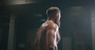 Spor salonunda vücudunda buhar olan yorgun sakallı adam idmandan sonra iyileşiyor.