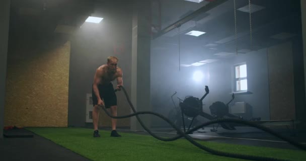 Fitness férfi gyakorol harci kötéllel elhagyott raktárban. Kemény ember edz a régi gyárban gyártott edzőteremben.. — Stock videók