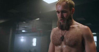 Spor salonundaki yoğun egzersizden sonra yorgun gençler dinleniyor. Yorgun erkek sporcu antrenmandan sonra dinleniyor. Yüzünden bir damla su akıyor, spor salonunda egzersiz yapıyor.