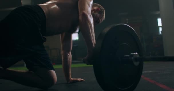 Een sterke man wordt aan de ene kant in de sportschool geduwd met een damp op zijn lichaam. — Stockvideo