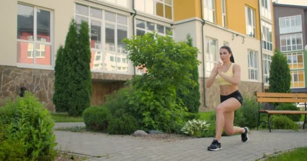 A lábak és csípők edzése a városi parkban. Fiatal nő teszi tüdő a városi parkban a sétányon — Stock videók