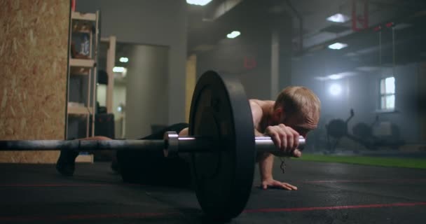 Чоловік штовхає штангу однією рукою на підлозі спортзалу в повільному русі — стокове відео