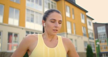 Eğitimden önce ısınma ve ısınma kaslarını tamamlamak için. Parkta kulaklıklı bir kadın başarılı bir spor sonrası esneme hareketleri sergiliyor. Gücünü geri kazan 