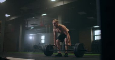 Spor salonunda ağırlık kaldıran bir adam. Romen halterleri ağır çekimde spor salonunda halterle kaldırıyor