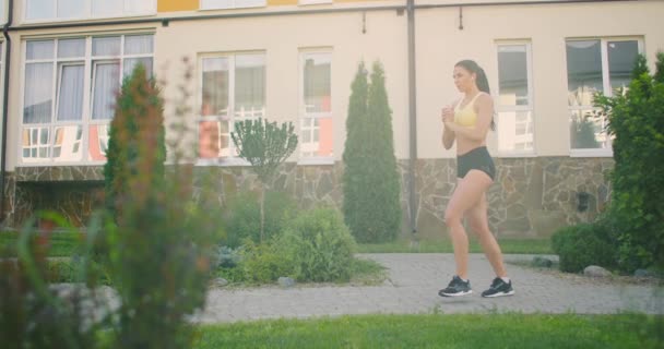 Trening nóg i bioder w parku miejskim. Młoda kobieta wykonuje lonże w parku miejskim na chodniku — Wideo stockowe