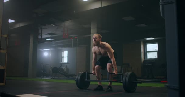 Atlético Bonito homem faz Deadlift com um Barbell no ginásio. Exercícios de levantamento de peso de musculação profissional masculino lindo na instalação de treinamento de ajuste autêntico . — Vídeo de Stock