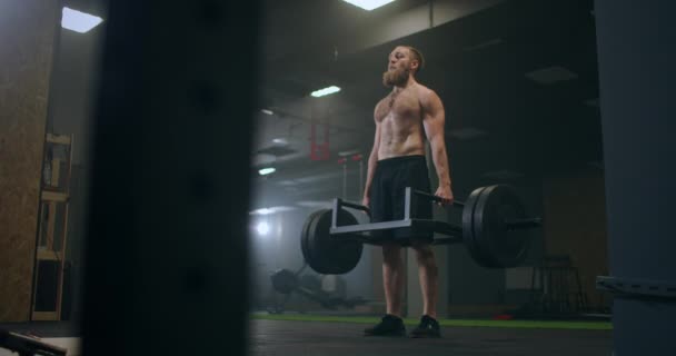 Atlético Bonito homem faz Deadlift com um Barbell no ginásio. Exercícios de levantamento de peso de musculação profissional masculino lindo na instalação de treinamento de ajuste autêntico . — Vídeo de Stock