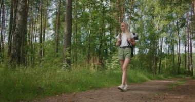 Genel plan: Seyahat eden mutlu beyaz kadın sırt çantasıyla tropikal ormanda yürüyor. 