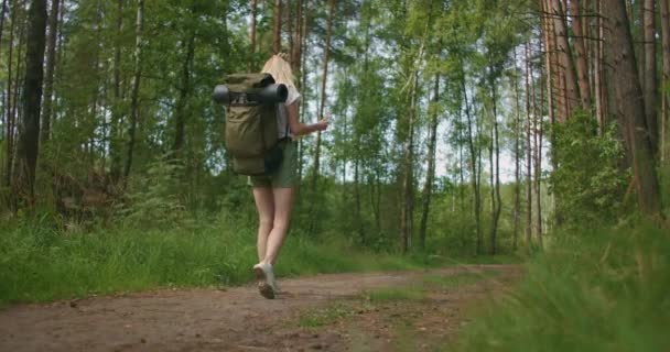 Zeitlupe Rückansicht: Junge Kaukasierin auf der Suche nach Orientierung auf einer Landkarte beim Wandern im Wald. Glückliches Mädchen beim Wandern in der Natur und Orientierungslauf mit Hilfe einer Karte — Stockvideo