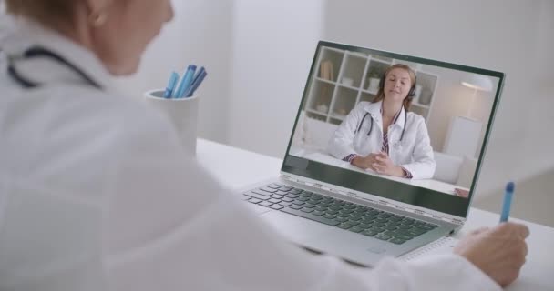 Internetkonsultation av två kvinnliga terapeuter, som talar med videosamtal, med bärbar dator med webbkamera och internet. — Stockvideo