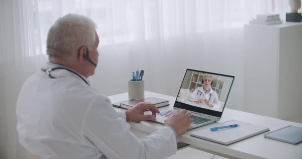 Врачи общаются онлайн, разговаривают и консультируют, врач-мужчина обращается к женщине-терапевту — стоковое видео