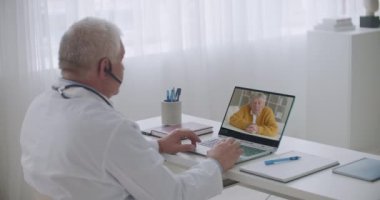 Gastroenteroloğun online randevusu, yaşlı erkek hasta internetten doktorla görüşüyor, belirtilerden bahsediyor.